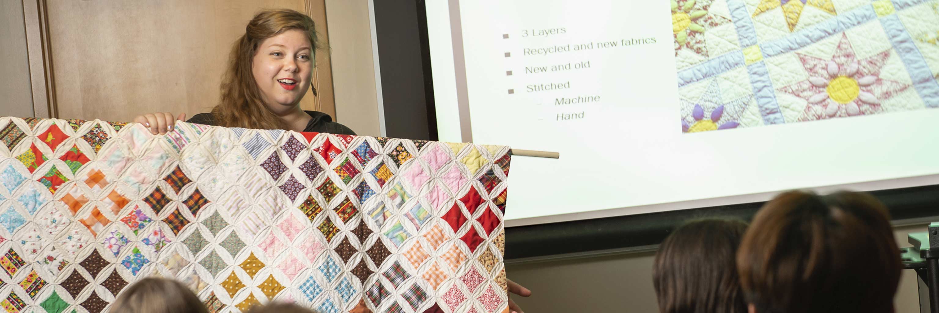 A graduate student presents a quilt to the class.