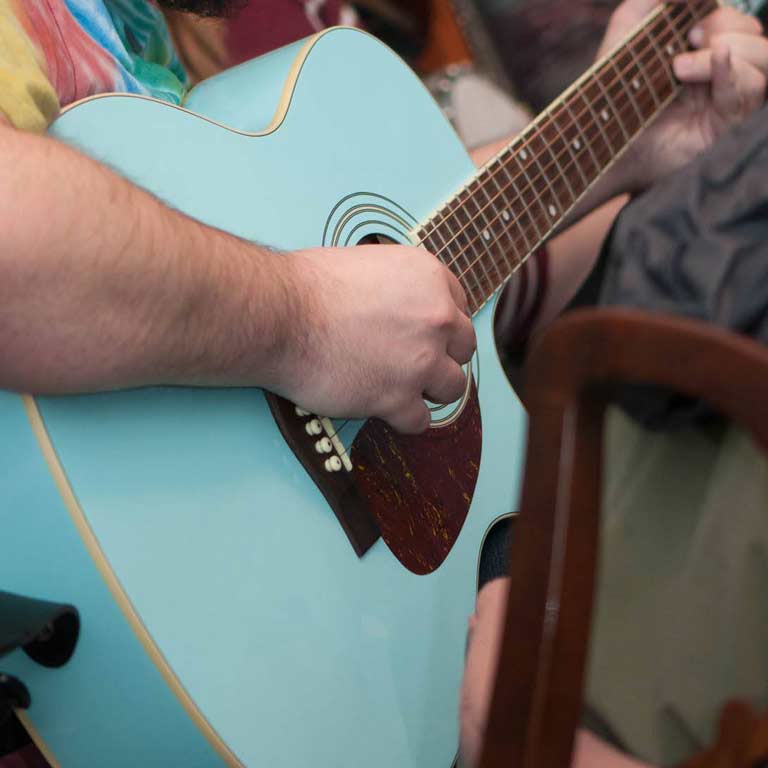 Close-up of person playing blue guitar. 