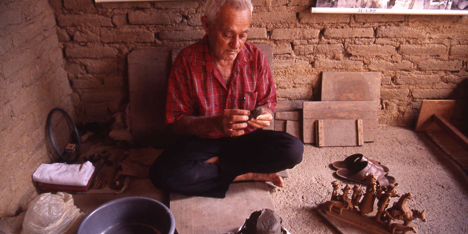Man holds wooden figurine. 