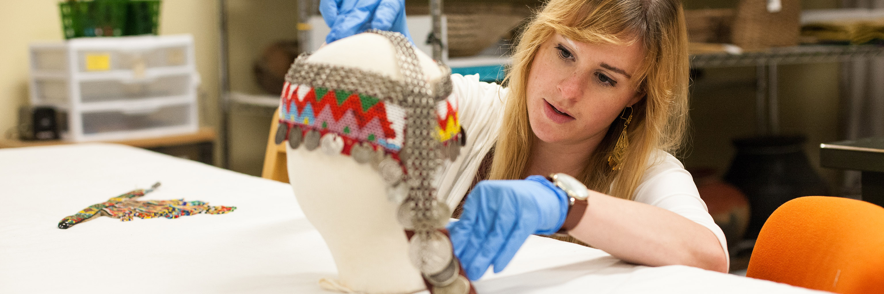 Student dresses a bust with a dorsal plate used as a ceremonial headdress in Syrian culture as part of the Clowes Internship Program at the Mathers Museum.